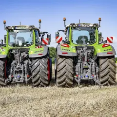 Dwa zielone traktory Fendt 724 Vario stojące na polu po żniwach, gotowe do pracy.