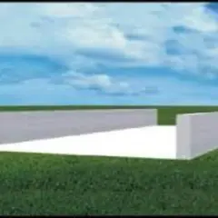 Budowa płyty obornikowej w trakcie. Betonowe ściany tworzą prostokąt na zielonej łące pod błękitnym niebem.